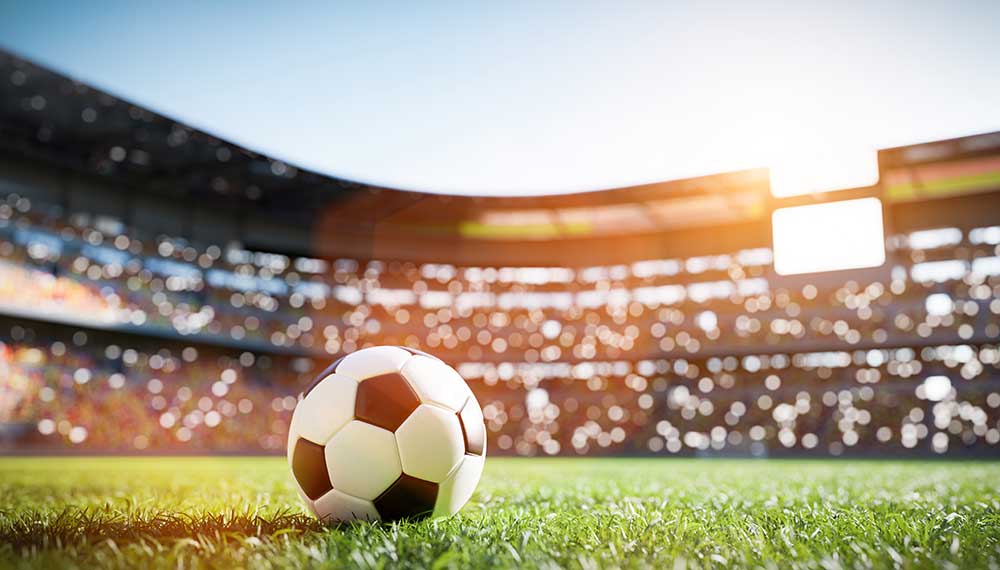 Soccer ball on pitch with stadium in backgrounds