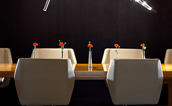 Meeting room with wide white chairs and red flowers on table
